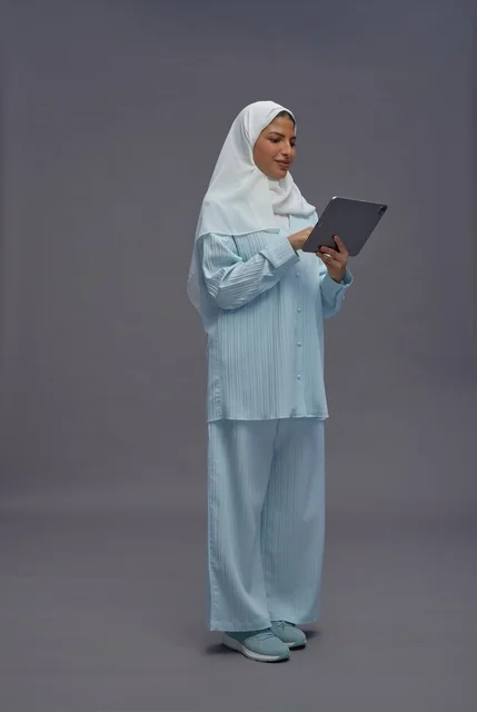 امرأة سعودية بزي محتشم تستخدم جهاز لوحي في الاستوديو