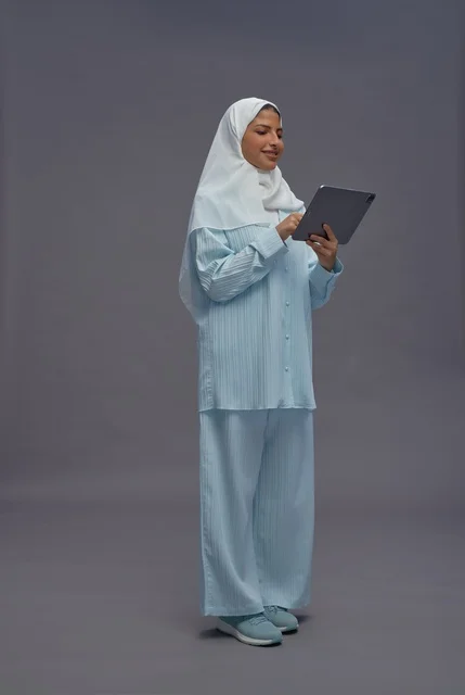 امرأة سعودية بزي محتشم تستخدم جهازاً لوحياً في استوديو