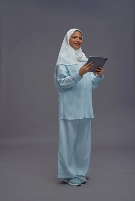 امرأة سعودية بزي محتشم تمسك بجهاز لوحي ذكي