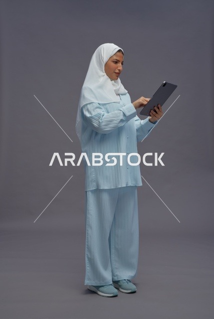 امرأة سعودية بزي محتشم تستخدم جهاز لوحي