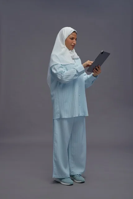 امرأة سعودية بزي محتشم تستخدم جهاز لوحي