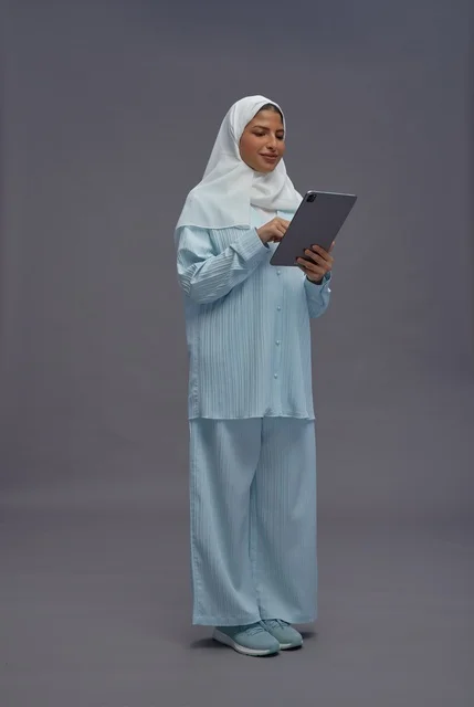 امرأة سعودية تستخدم جهاز لوحي بملابس كاجوال محتشمة
