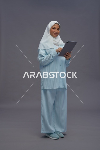 امرأة سعودية تستخدم جهاز لوحي بزي كاجوال محتشم