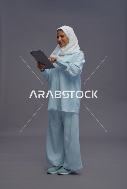 امرأة سعودية تستخدم جهاز لوحي بزي كاجوال محتشم
