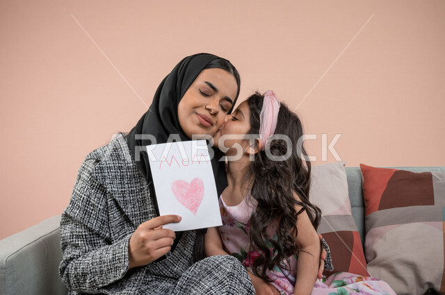 بورتريه لطفلة عربية خليجية سعودية تقبل امها ، تقدم الورود الجميلة وبطاقة المعايدة لوالدتها بايماءات تدل على الفرح والسعادة ، هدية يوم الأم ، عيد أم سعيد ،  عيد ميلاد ، اعياد ومناسبات سعيدة 