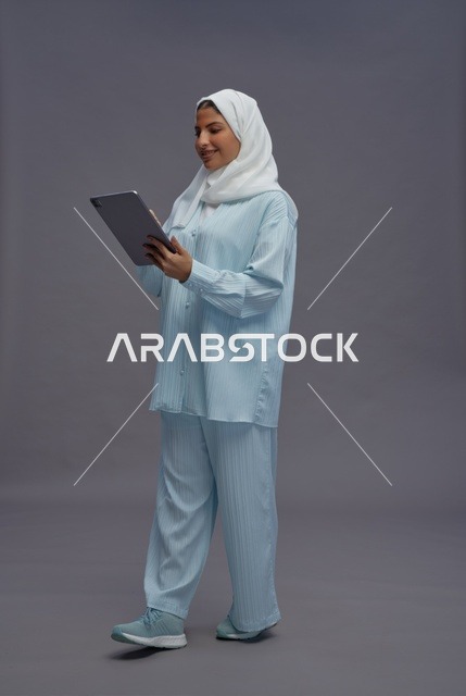 امرأة سعودية تستخدم جهاز لوحي بزي كاجوال محتشم