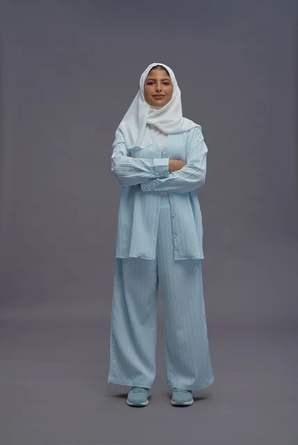 امرأة سعودية بزي كاجوال محتشم على خلفية رمادية