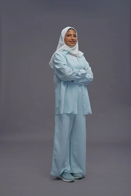 امرأة سعودية بزي كاجوال محتشم على خلفية رمادية