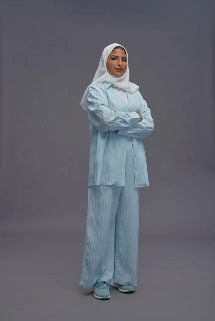 امرأة سعودية بزي كاجوال محتشم على خلفية رمادية