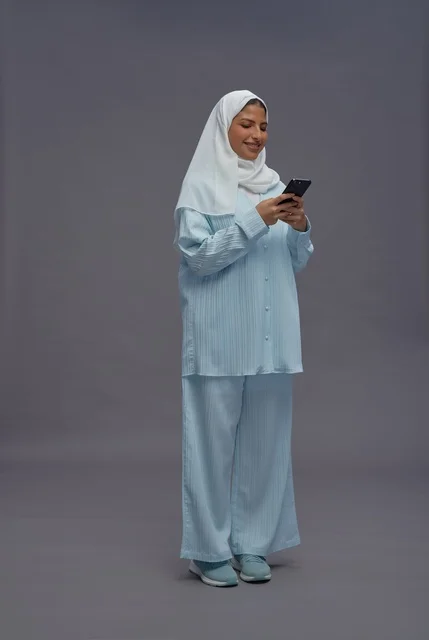 امرأة سعودية تستخدم الهاتف الذكي بزي كاجوال محتشم