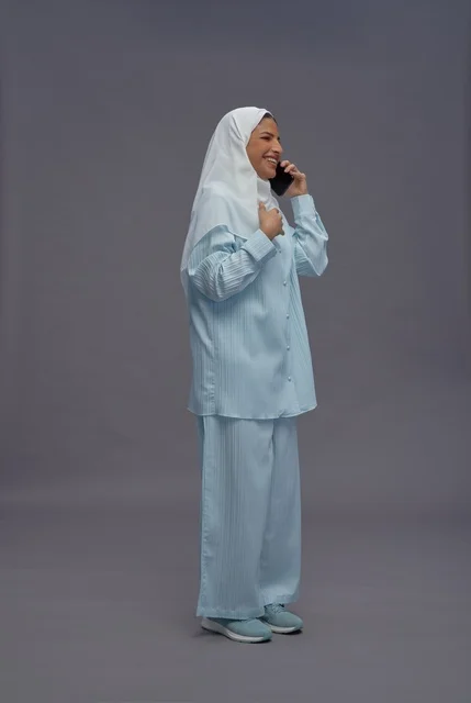 امرأة سعودية بزي كاجوال تتحدث على الهاتف الذكي