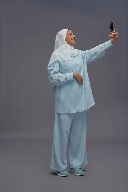 امرأة سعودية بالحجاب تلتقط صورة سيلفي بالهاتف