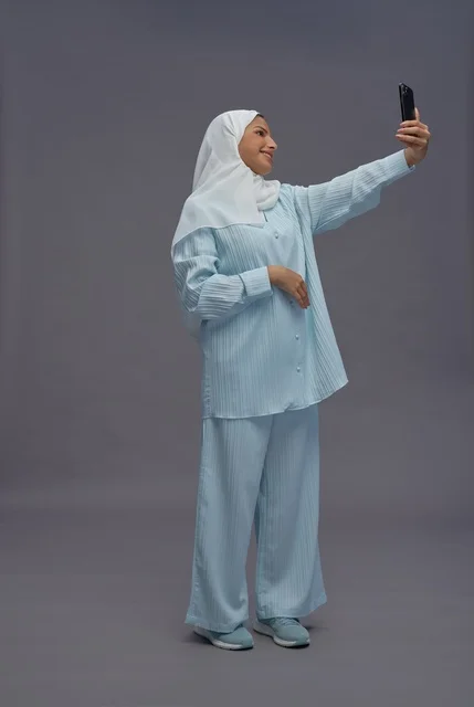 امرأة سعودية بالحجاب تلتقط صورة سيلفي بالهاتف الذكي