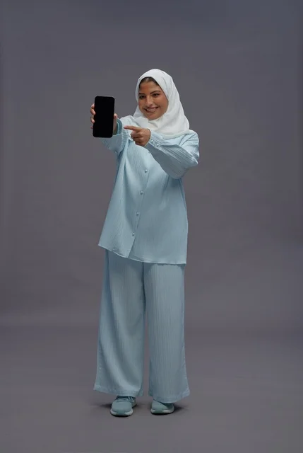 امرأة سعودية تحمل هاتف ذكي وتشير للشاشة