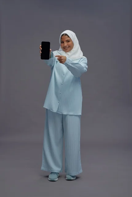 امرأة سعودية بالحجاب تحمل هاتف ذكي بشاشة فارغة