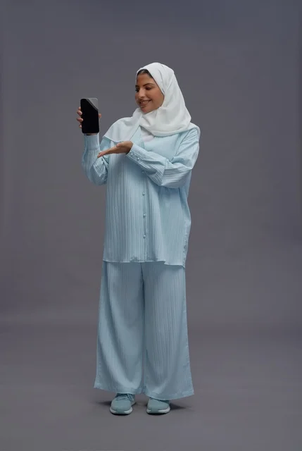 Saudi Woman Wearing Hijab Holding Smartphone in Studio