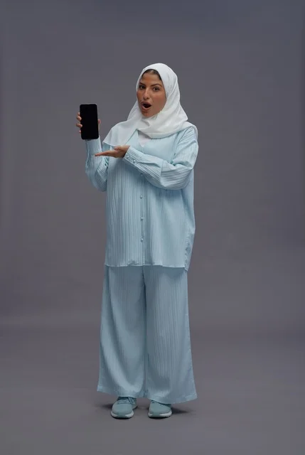 Saudi Woman with Hijab Holding Smartphone on Grey Background