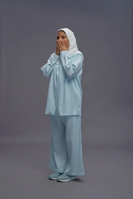 امرأة سعودية بزي كاجوال أزرق وحجاب أبيض تعبر عن المفاجأة