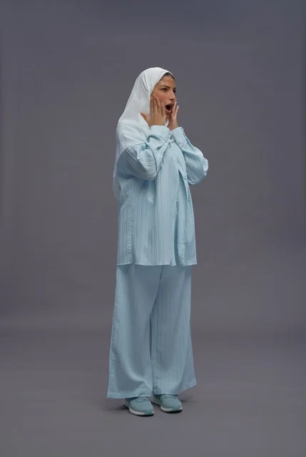 امرأة سعودية بزي كاجوال أزرق بتعبير وجه مصدوم