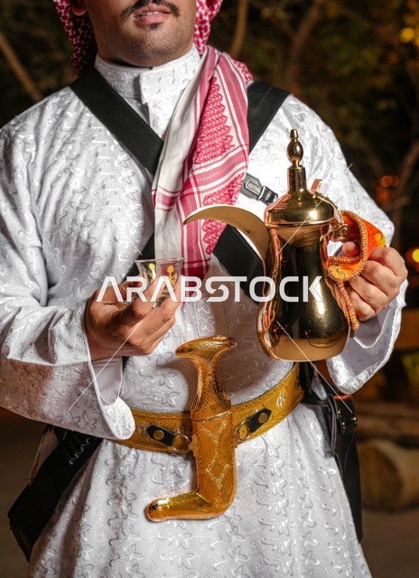رجل سعودي بالزي التقليدي يحمل دلة القهوة والجنبية