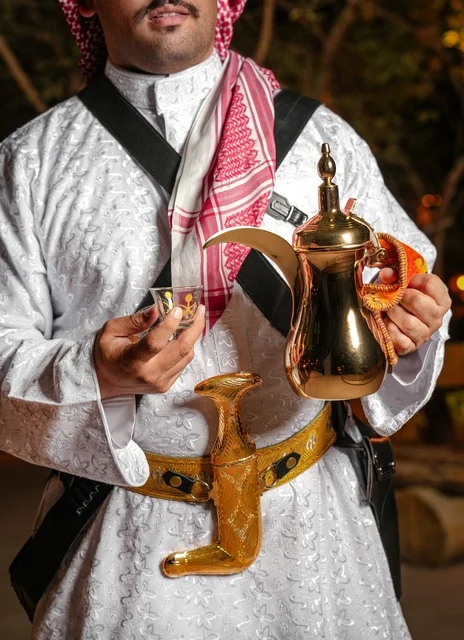 رجل سعودي بالزي التقليدي يحمل دلة القهوة والجنبية