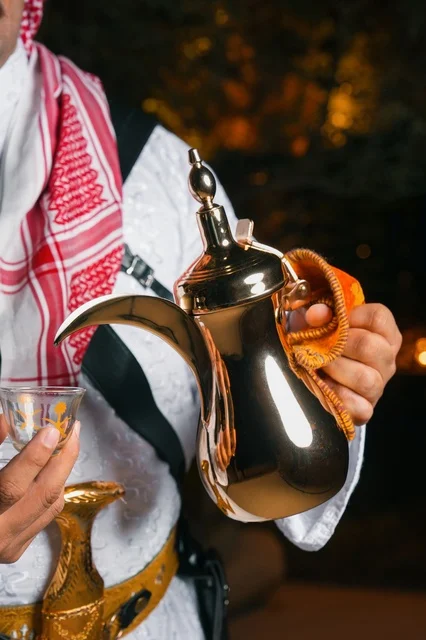 Saudi Man Pouring Arabic Coffee from Golden Dallah