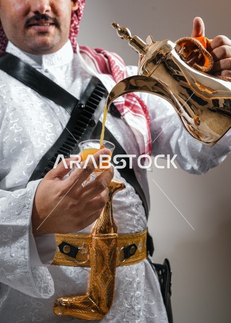 رجل سعودي بالزي الشعبي يصب القهوة العربية