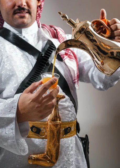 Saudi Man in Traditional Dress Pouring Arabic Coffee