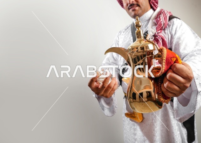 رجل سعودي يحمل دلة قهوة ذهبية تقليدية