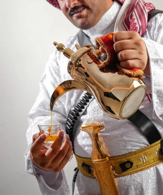 Saudi Man Pouring Arabic Coffee from Golden Dallah