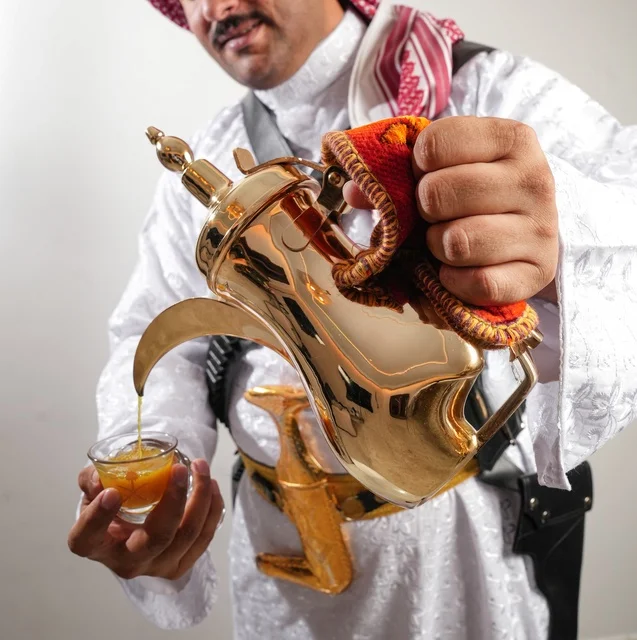 Saudi Man Pouring Arabic Coffee from Golden Dallah