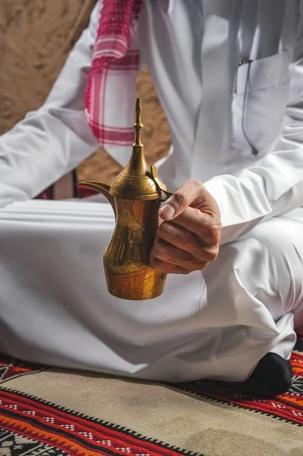 رجل سعودي يمسك بدلة القهوة العربية التقليدية