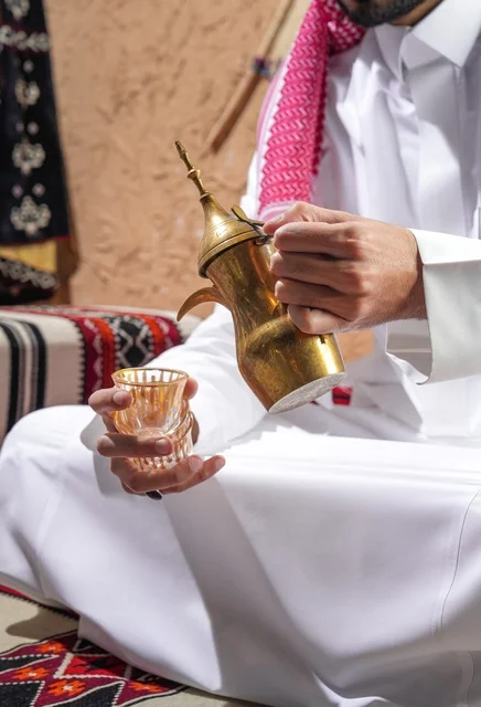 Saudi Man Pouring Arabic Coffee from Golden Dallah