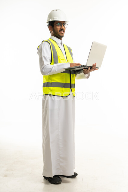 مهندس سعودي يحمل لابتوب بملابس السلامة