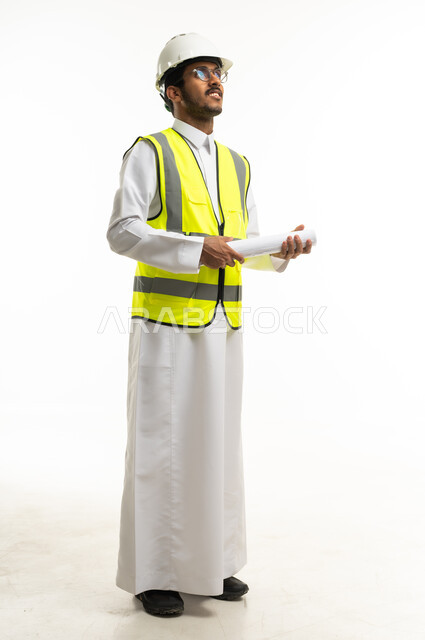مهندس سعودي يمسك مخططات هندسية بزي السلامة