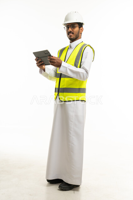 مهندس سعودي يرتدي سترة السلامة ويحمل جهاز لوحي