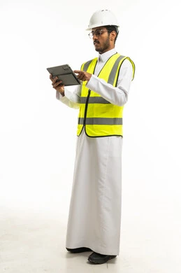 مهندس سعودي يرتدي سترة السلامة ويستخدم جهاز لوحي