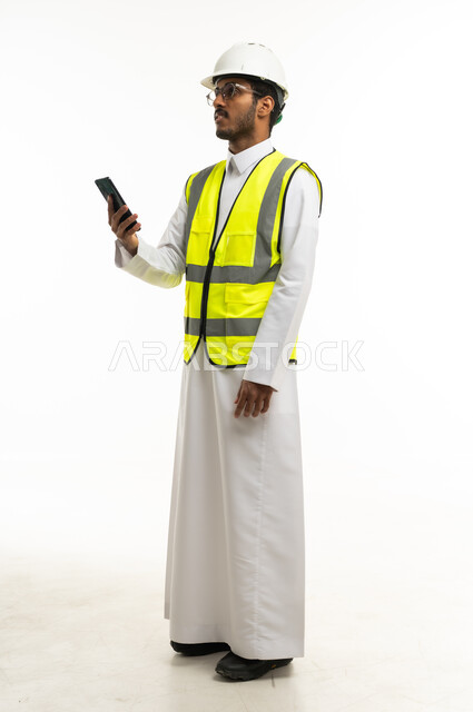 مهندس سعودي يرتدي سترة السلامة ويحمل هاتف ذكي