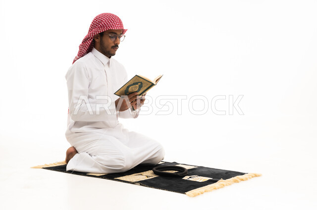 رجل سعودي يقرأ القرآن الكريم على سجادة الصلاة