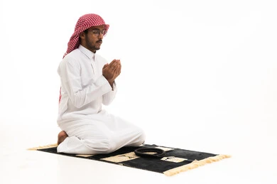 رجل سعودي يصلي على السجادة بخلفية بيضاء