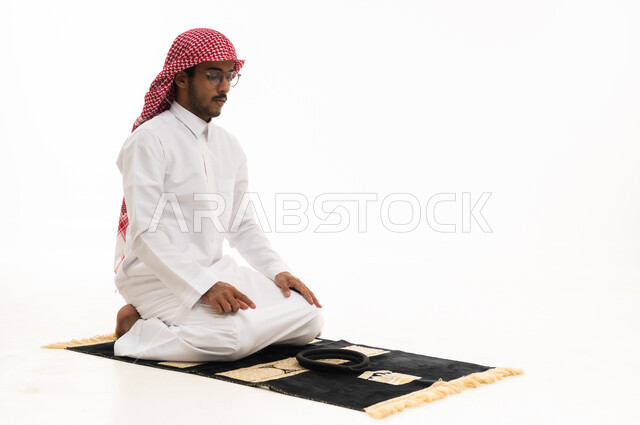 رجل سعودي يصلي على سجادة صلاة خلفية بيضاء