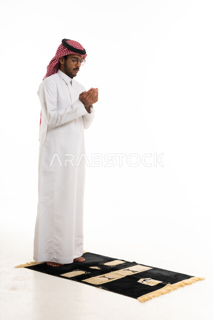 Saudi Man Praying on Mat Against White Background