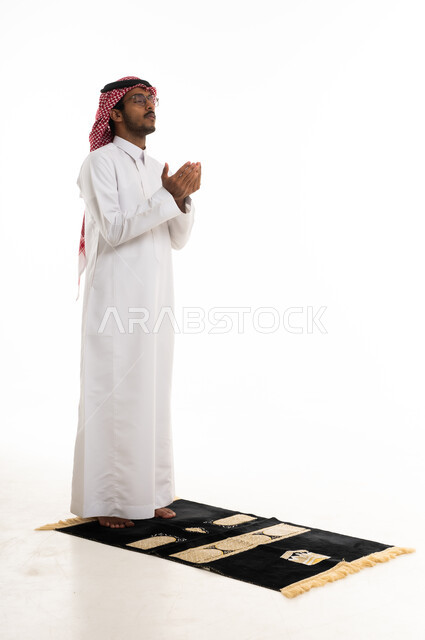 Saudi Man in Traditional Thobe Making Dua on Prayer Rug