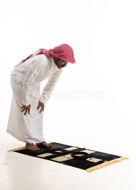 رجل سعودي يؤدي الركوع في الصلاة بخلفية بيضاء