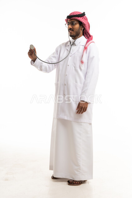 طبيب سعودي يحمل سماعة طبية بخلفية بيضاء