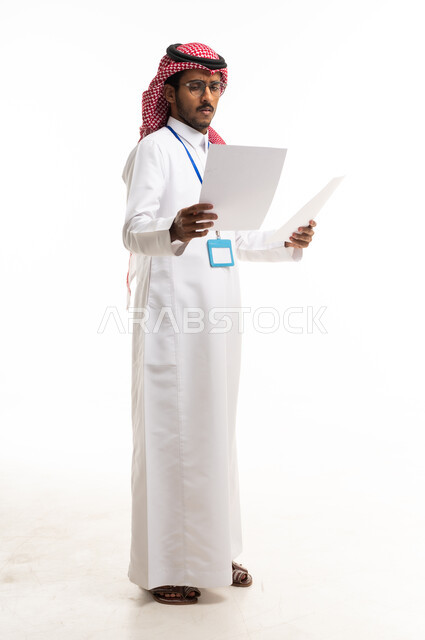 موظف سعودي بالزي التقليدي يراجع الأوراق في الاستوديو