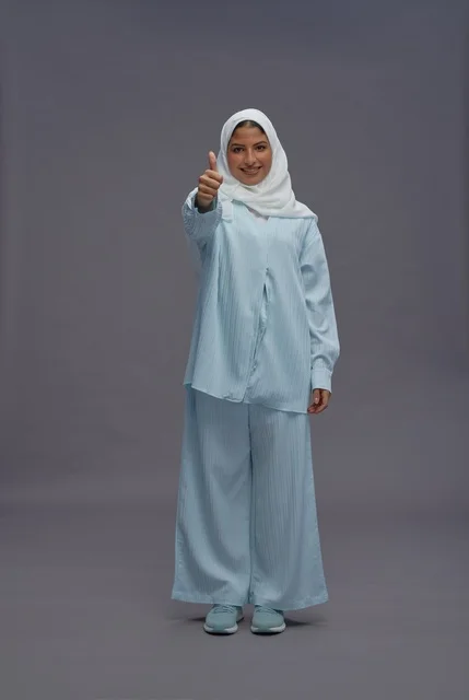 امرأة سعودية تشير بالإبهام بزي أزرق محتشم
