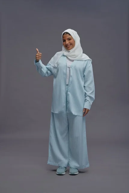 امرأة سعودية ترفع إبهامها بملابس محتشمة زرقاء