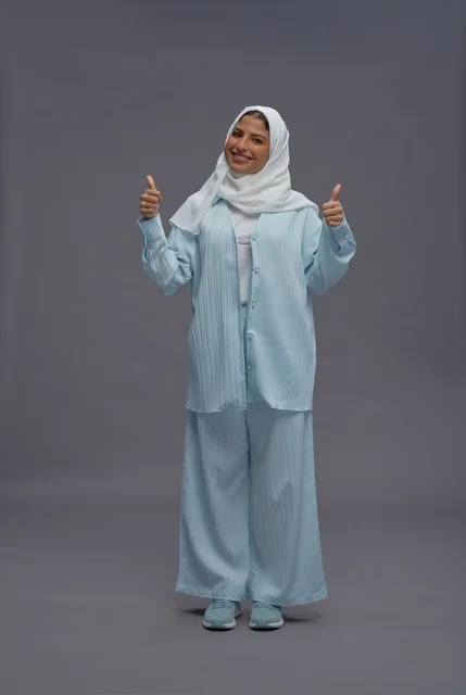 امرأة سعودية بزي أزرق محتشم تشير بالإبهام
