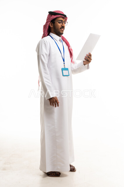 Saudi Man in Traditional Thobe Reading Paper on White Background